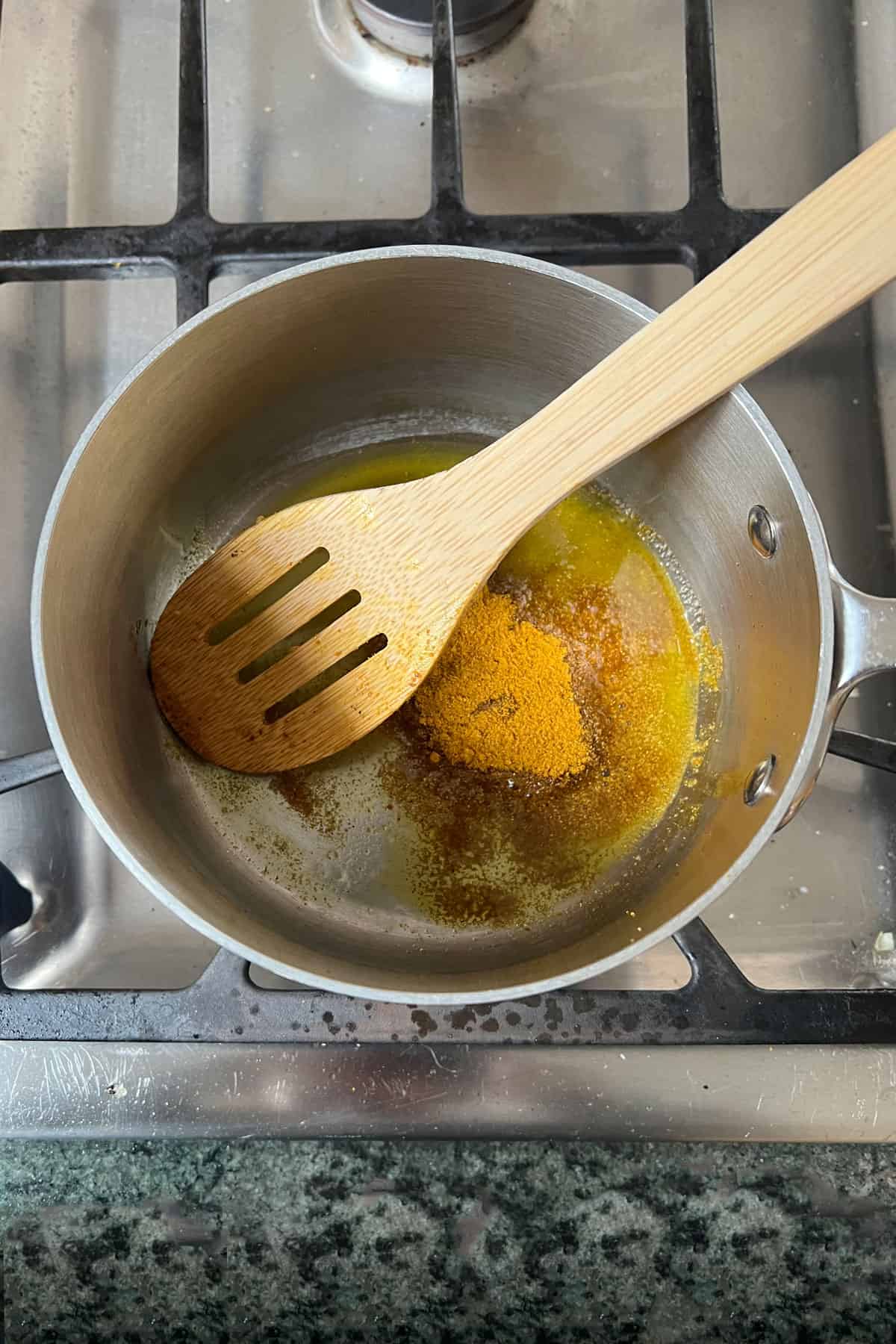 Olive oil and curry powder in a small sauce pan, stirring with a wooden spoon.