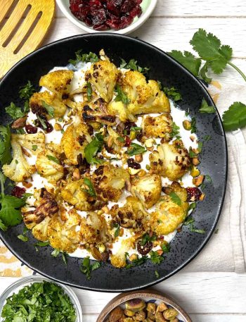Curried roasted cauliflower on a bed of yogurt topped with chopped toasted pistachios and cilantro.