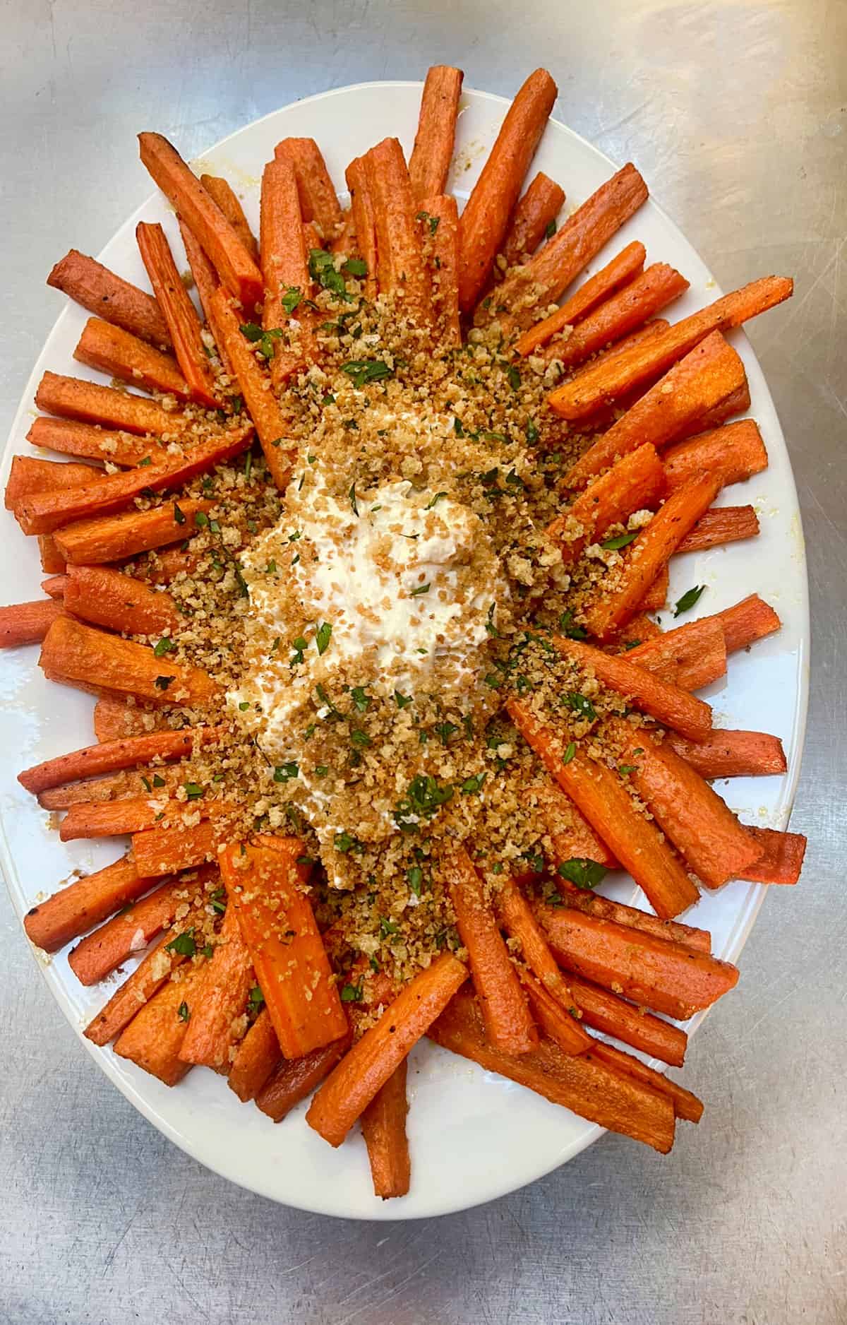 Platter topped with roasted carrot sticks arranged around a portion of whipped feta topped with toasted breadcrumbs.