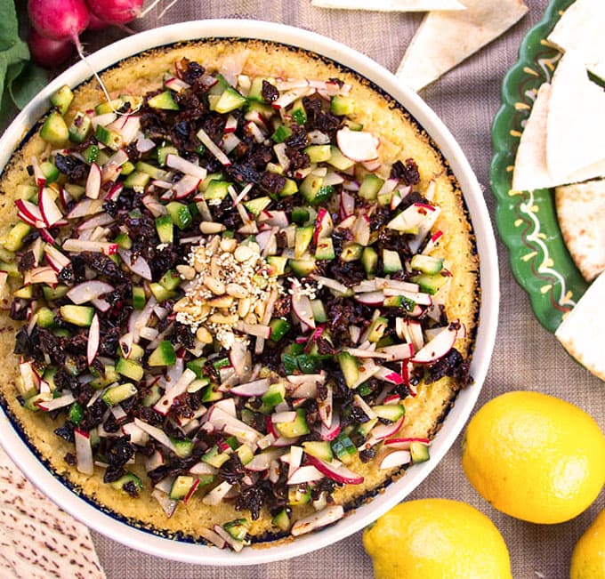 decorative pie pan filled with hot hummus, topped with a chopped salad and toasted pine nuts.