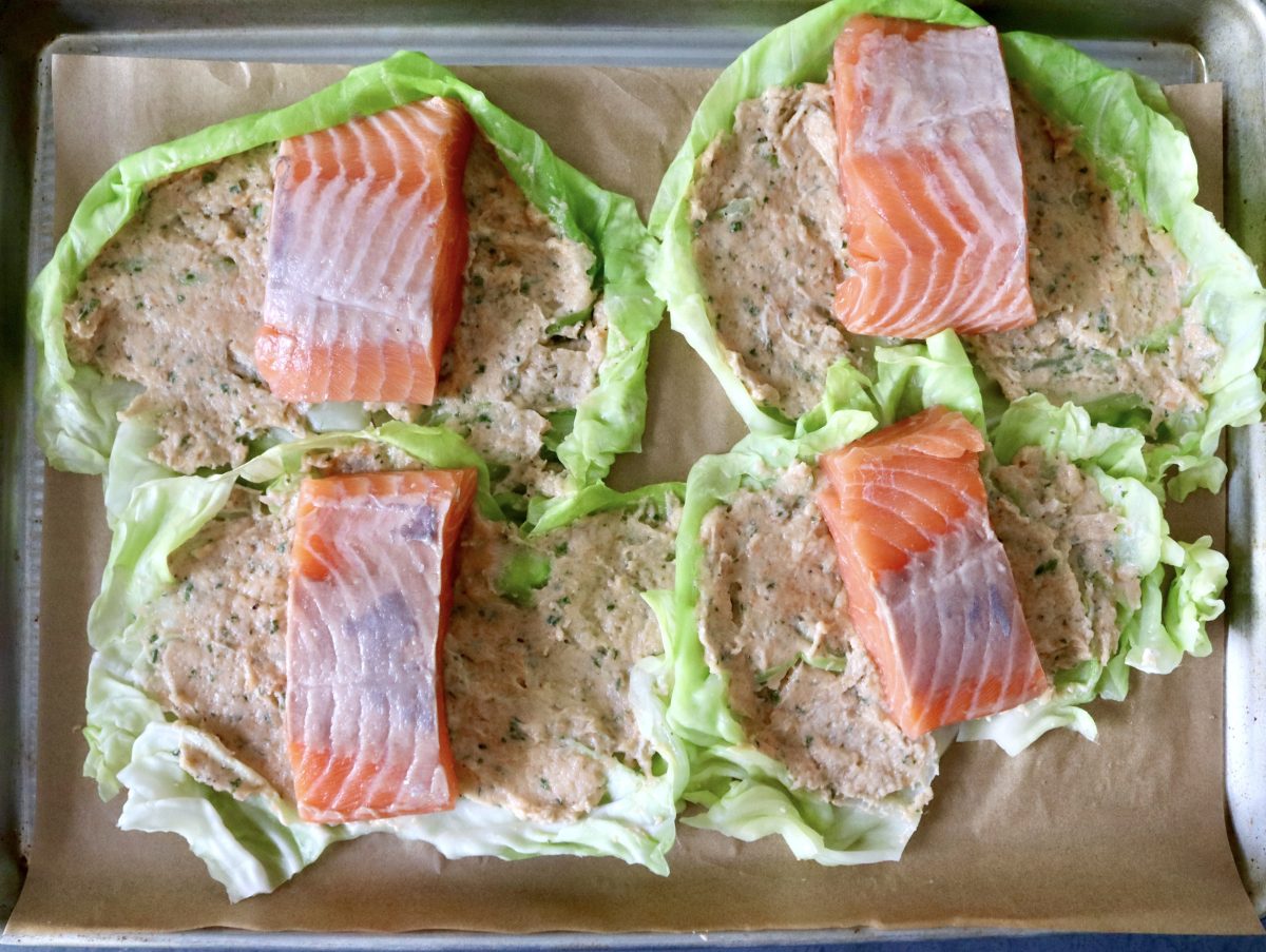 Four cabbage leaves spread with salmon mousse, with a salmon fillet on top.