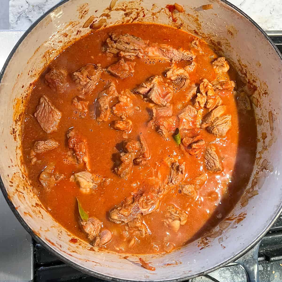 lamb and curry sauce ingredients in a dutch oven ready to be simmered. 