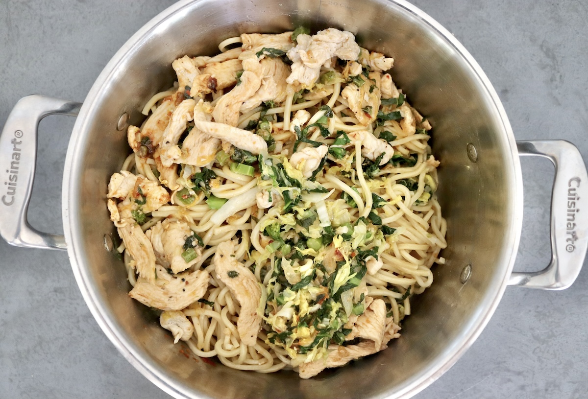 A large pot with steamed Chinese noodles, cabbage, Gai Lan and steamed chicken pieces - not mixed. 