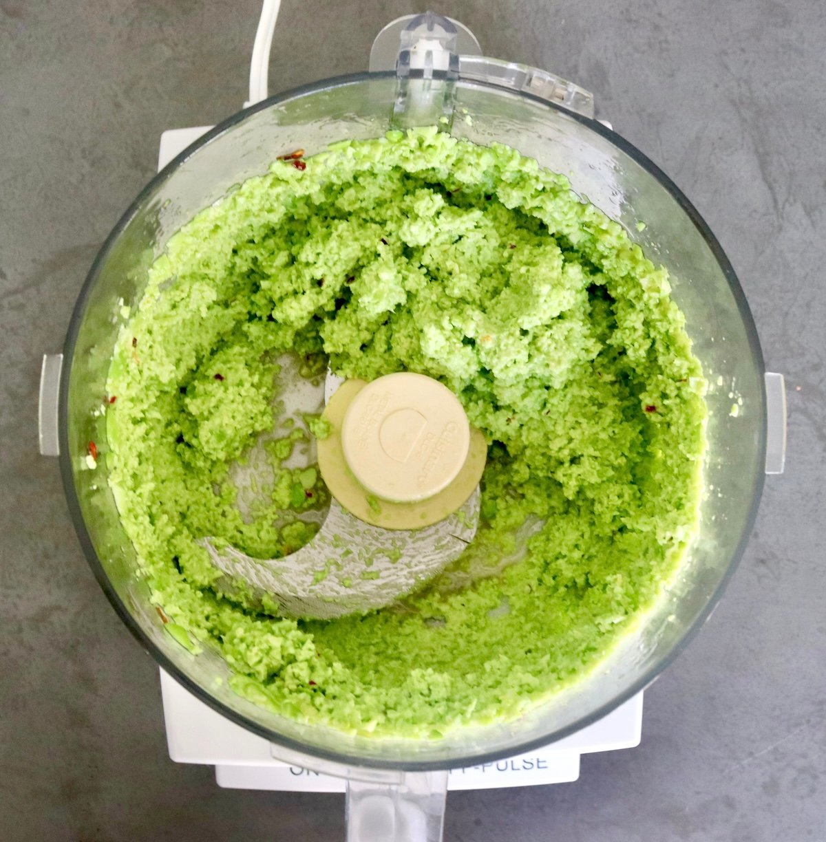 Food processor bowl with blade attachment and edamame pesto.