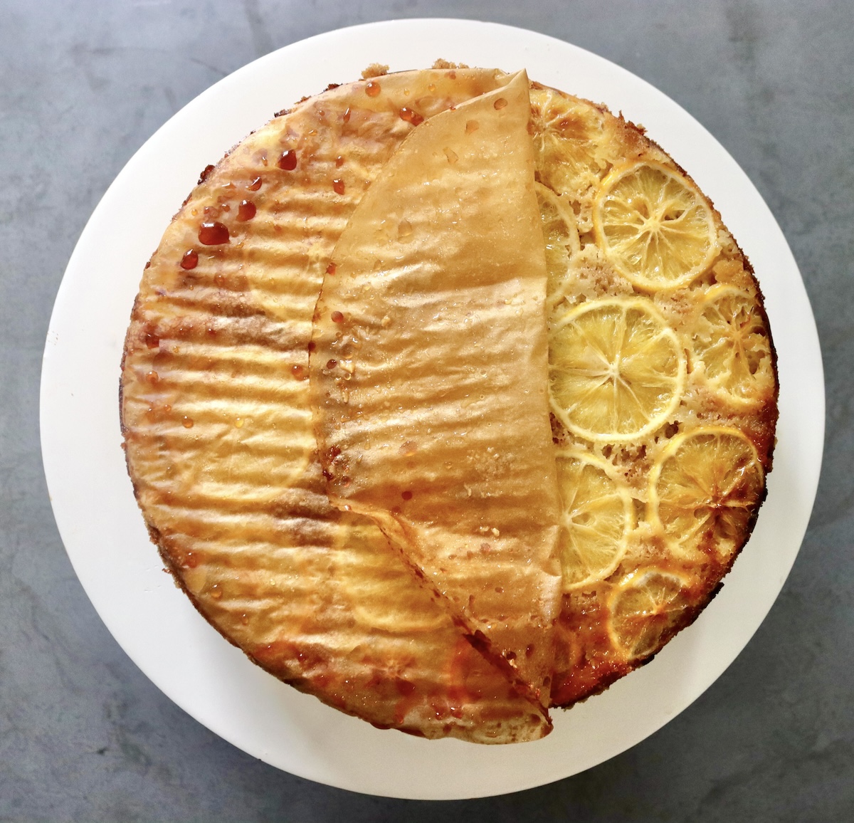 Lemon infused cake with parchment paper being peeled back to reveal the lemon wedges. 