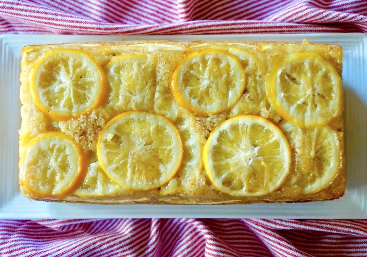 Lemon Loaf Cake with Olive Oil in a white plate with a red cloth under it.