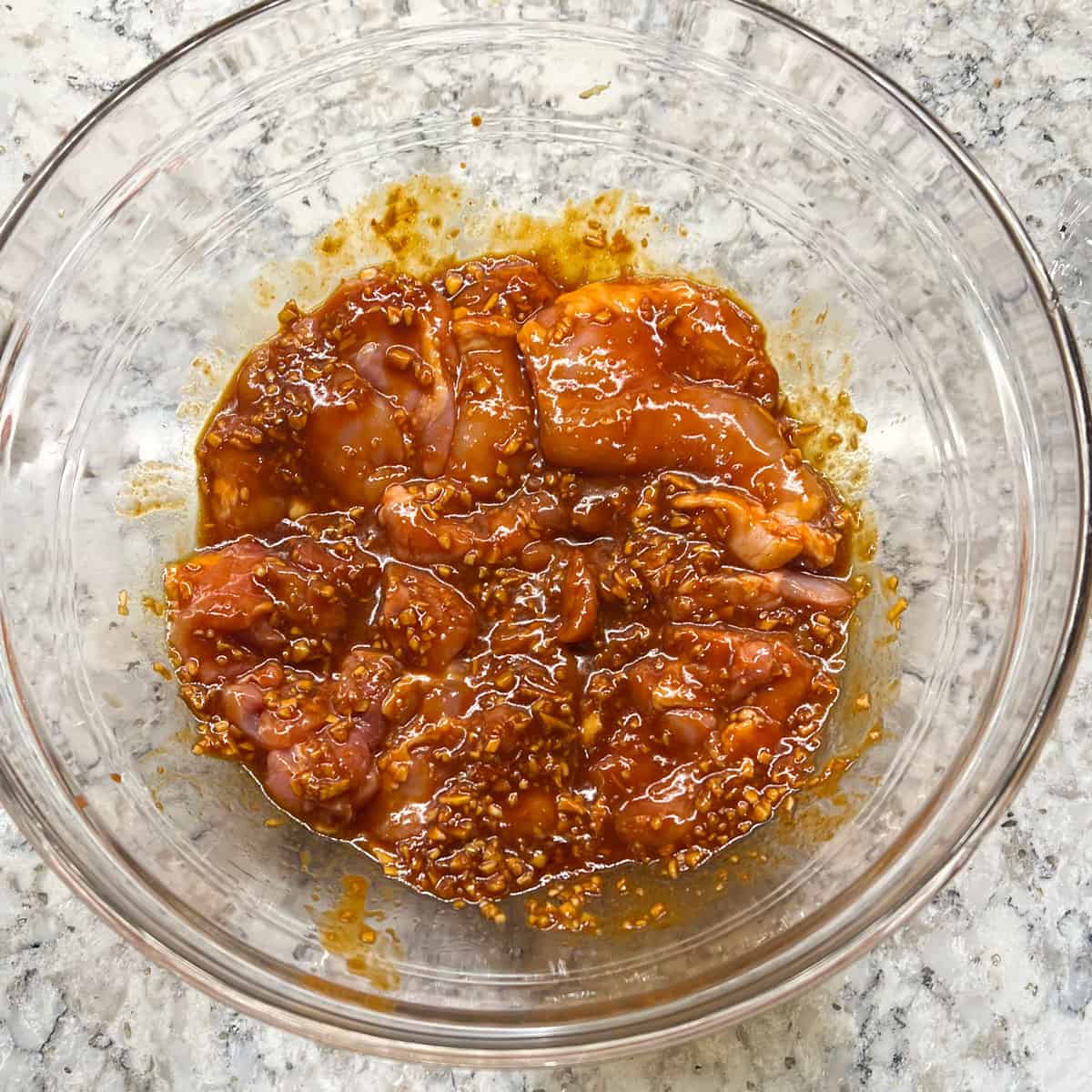 skinless chicken thighs marinated in chuchjang marinade in a glass mixing bowl