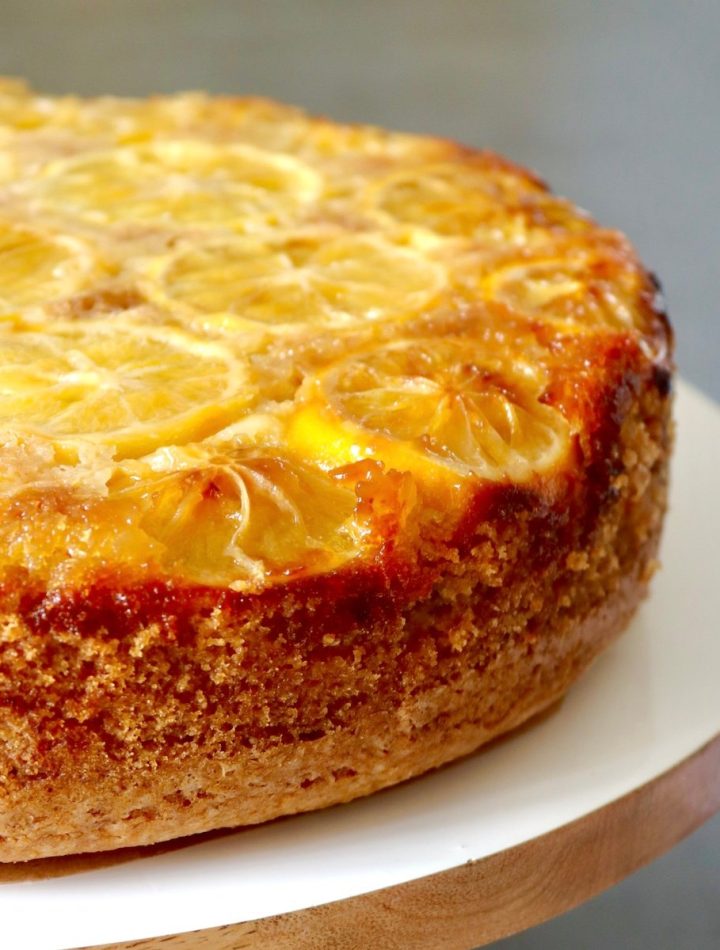 Whole Lemon Olive Oil Cake on white wood cake stand.