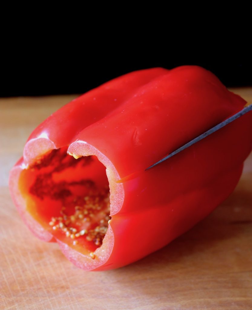 A red pepper is being cut on a cutting board