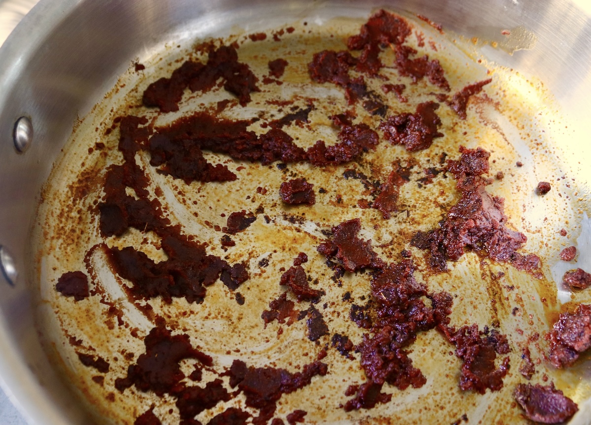 Browned tomato paste with spices in the bottom of the pan.