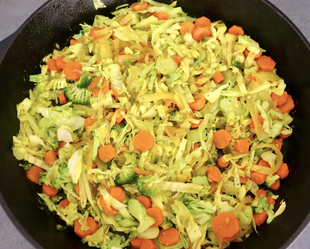 Hombe cast iron skillet yakazadzwa nesauteed kabichi, broccoli, hanyanisi uye makarotsi.