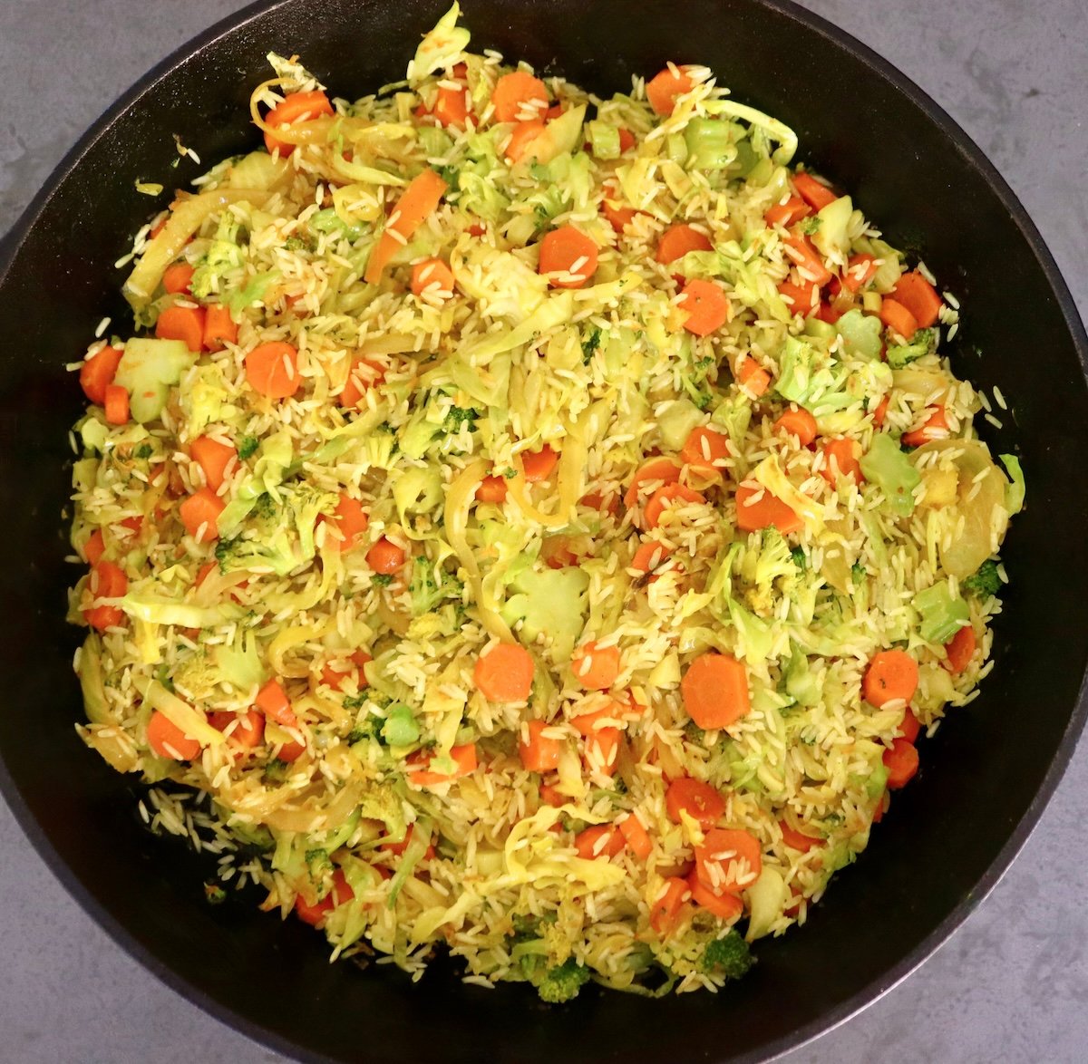 Hombe cast iron skillet yakazadzwa nesauteed cabbage, broccoli, hanyanisi makerotsi uye mupunga.