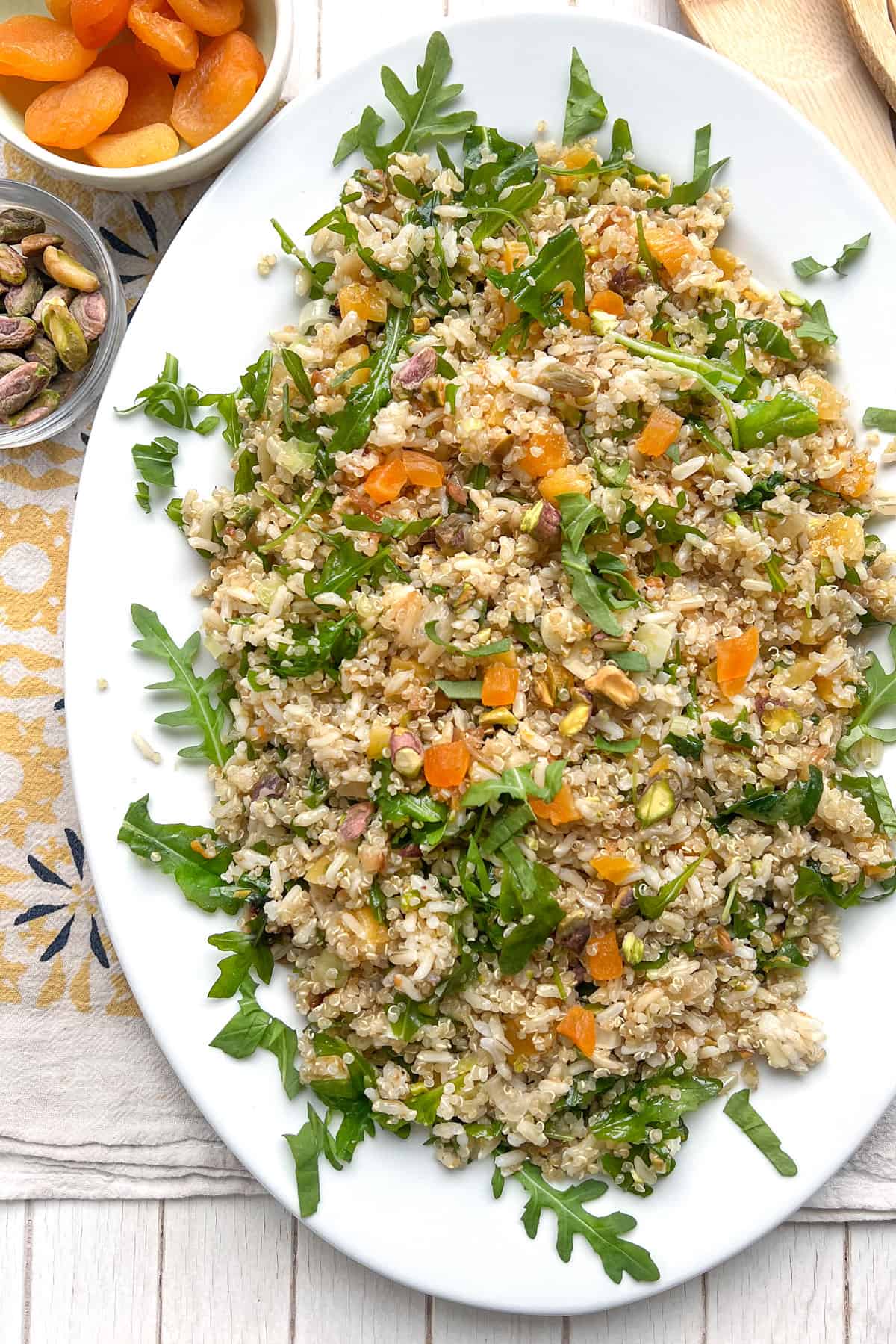 A bowl of omelette topped with rice and quinoa salad with chopped apricots, pistachios and arugula.