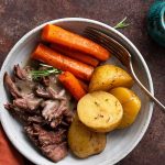 beef chuck roast dutch oven meal plated with vegetables and gravy