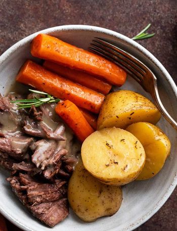 beef chuck roast dutch oven meal plated with vegetables and gravy