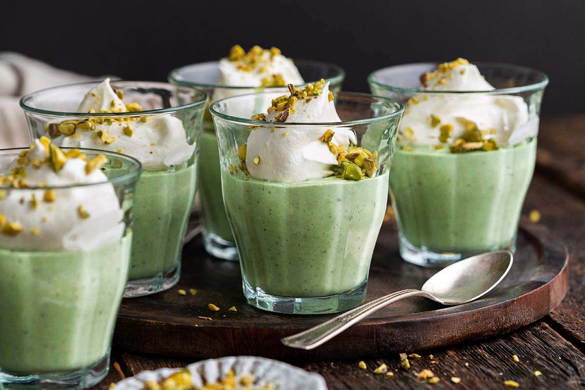 homemade pistachio pudding dessert in serving glasses on rustic wooden table