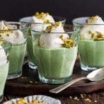 homemade pistachio pudding dessert in serving glasses on rustic wooden table