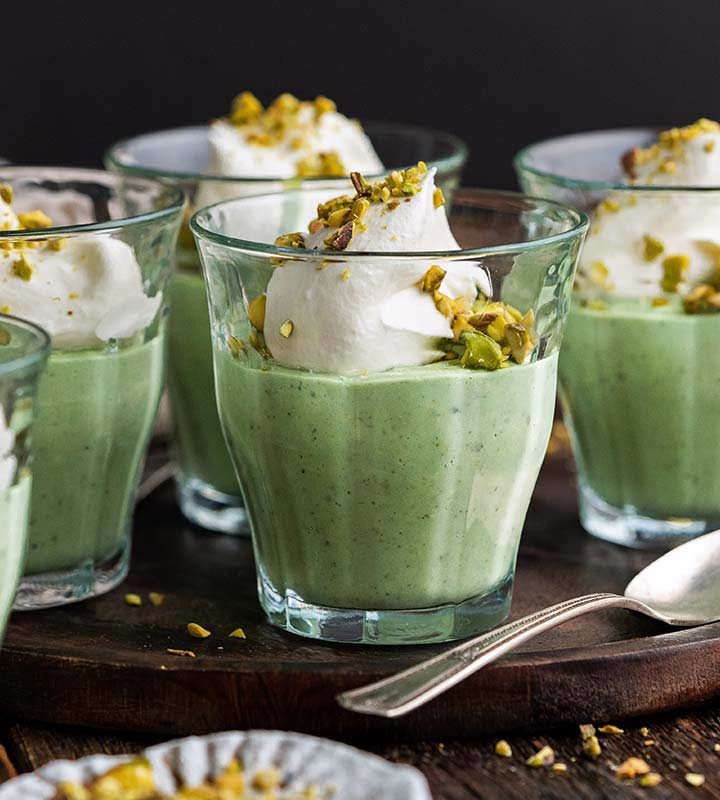 homemade pistachio pudding dessert in serving glasses on rustic wooden table