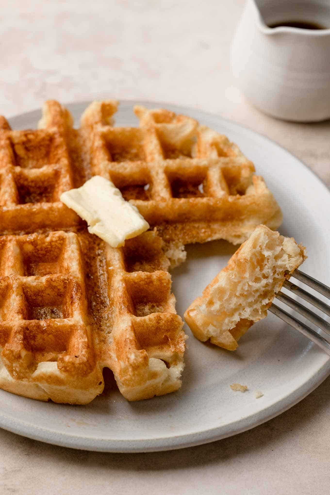 a slice of vegan Belgian waffle skewered on a fork shows how the waffle is made